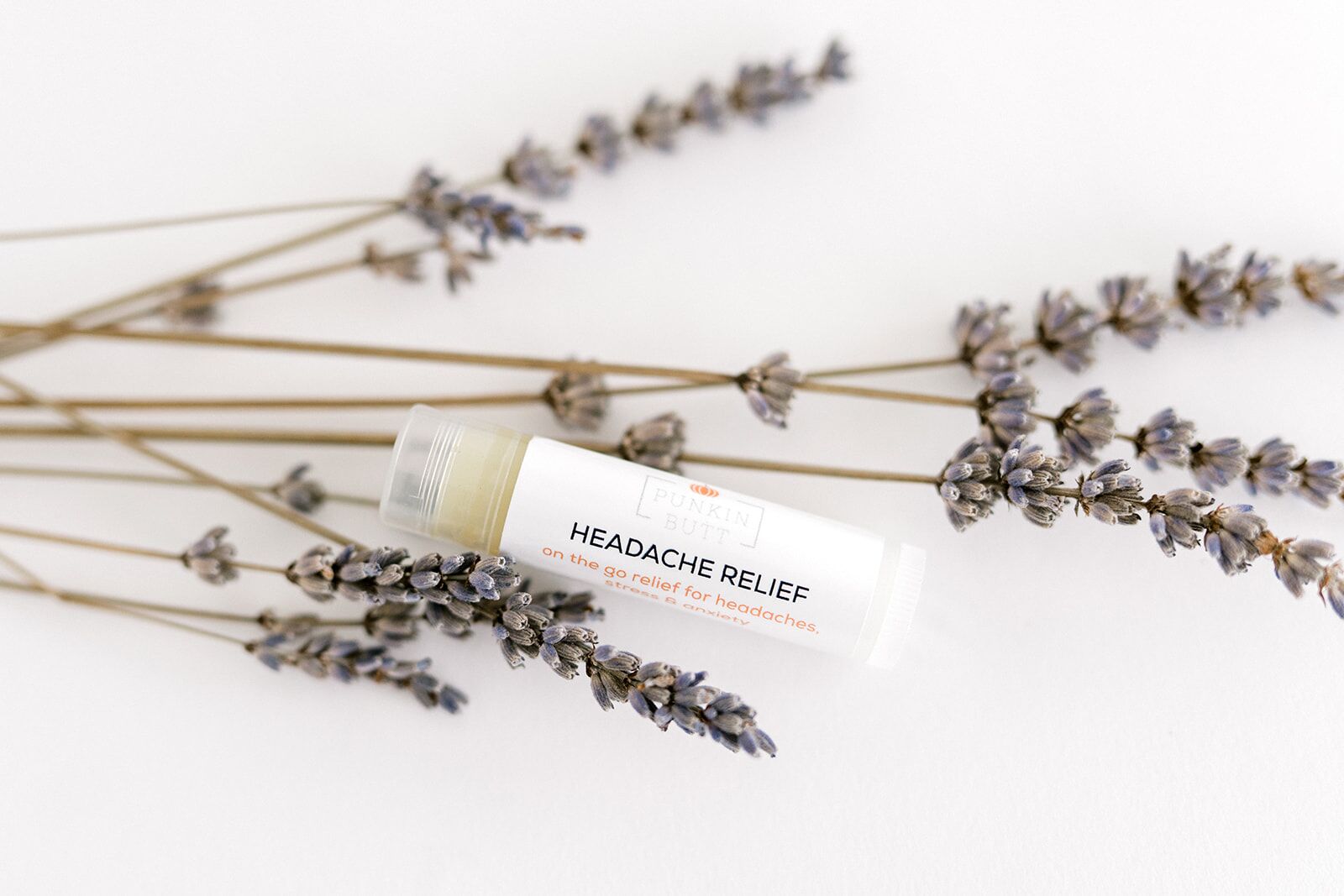 A tube of lavender oil sitting next to some flowers.
